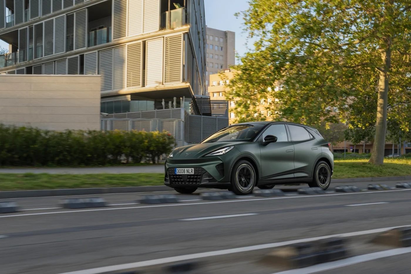 Green Cupra Raval driving past modern buildings
