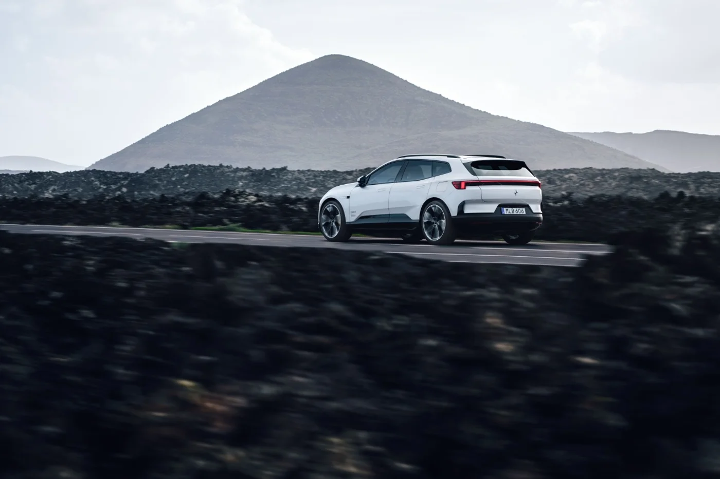 Polestar 4 SUV driving on a road with a mountain behind